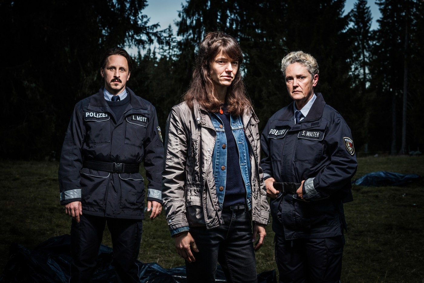 Eine uniformierte Polizistin, ein uniformierter Polizist und in der Mitte Sarah Spahle als Rosa Wilder