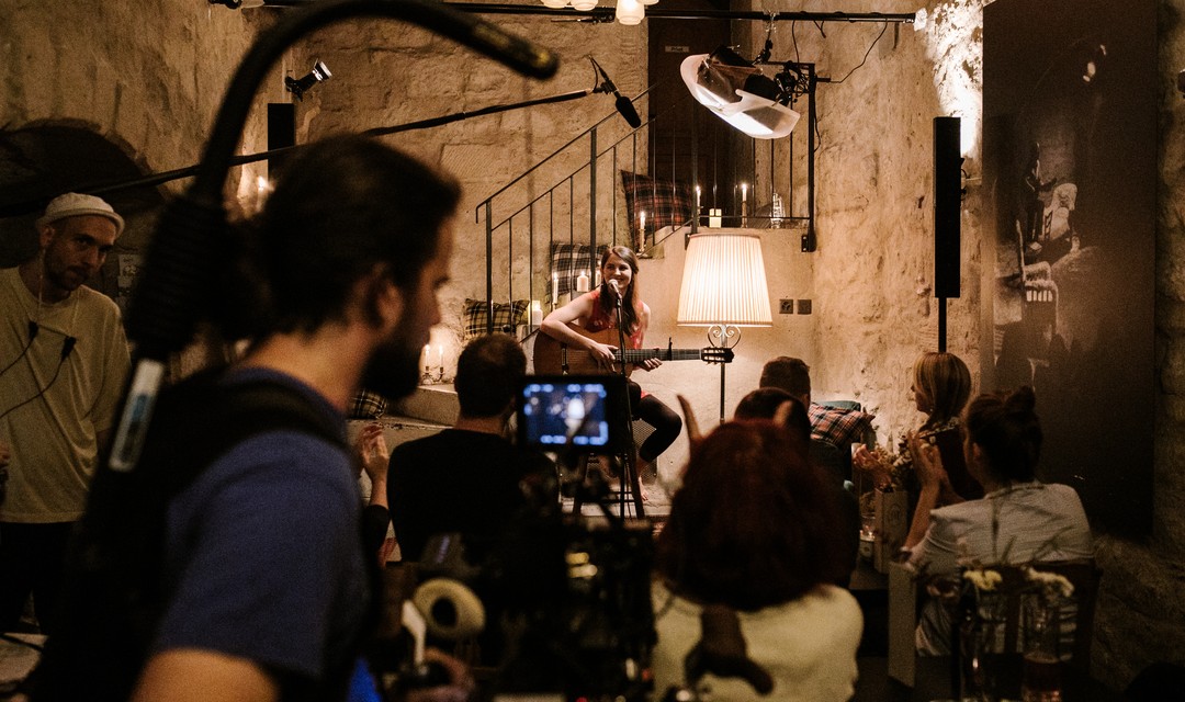 Hauptdarstellerin Lorena Handschin sitzt mit ihrer Gitarre vor dem Mikrofon in einem Club