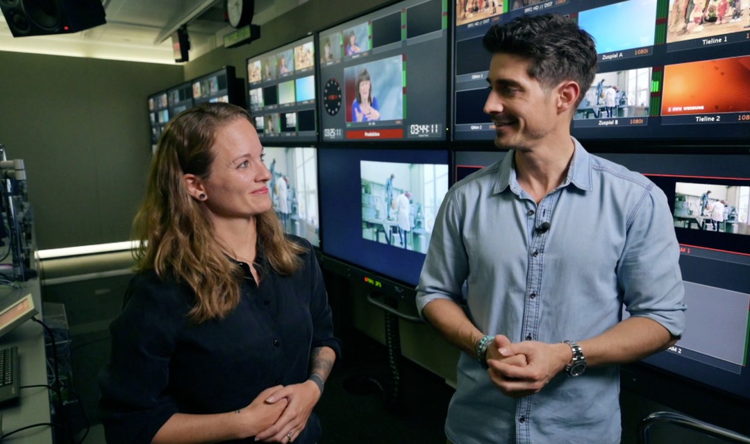 Tobias Müller und Natasha Ruf stehen nebeneinander in der TV-Regie und schauen sich an