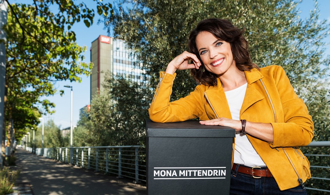 Mona steht vor dem Fernsehstudio in Leutschenbach und hält eine Überraschungsbox in der Hand