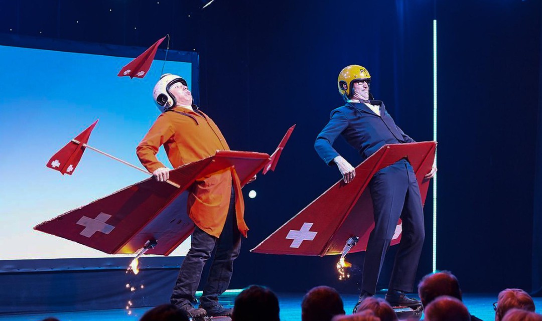 Das Comedy-Duo Lapsus steht im Pilotenkostüm auf der Bühne und hat sich einen Düsenjet aus Karton um die Hüfte geschnallt