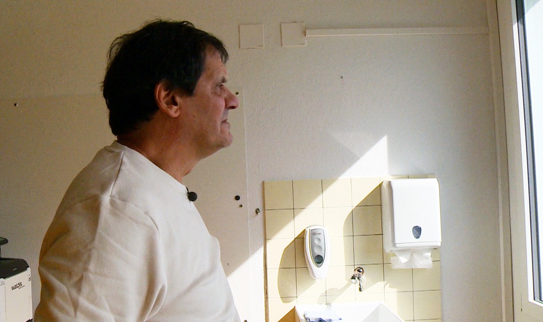 Mario Delfino steht in einem Badezimmer und blickt in die Ferne