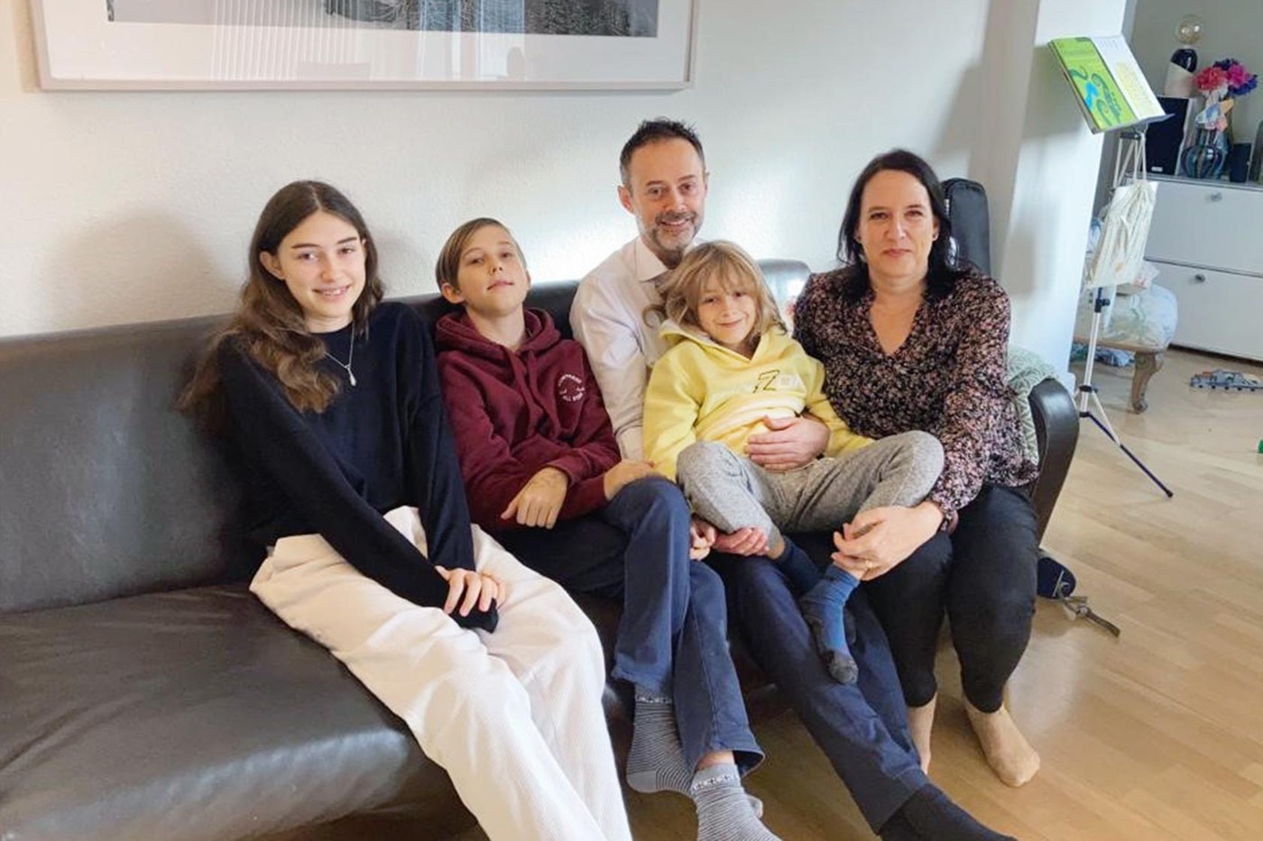 Die ganze Familie Balliana sitzt auf ihrem Sofa in Zürich