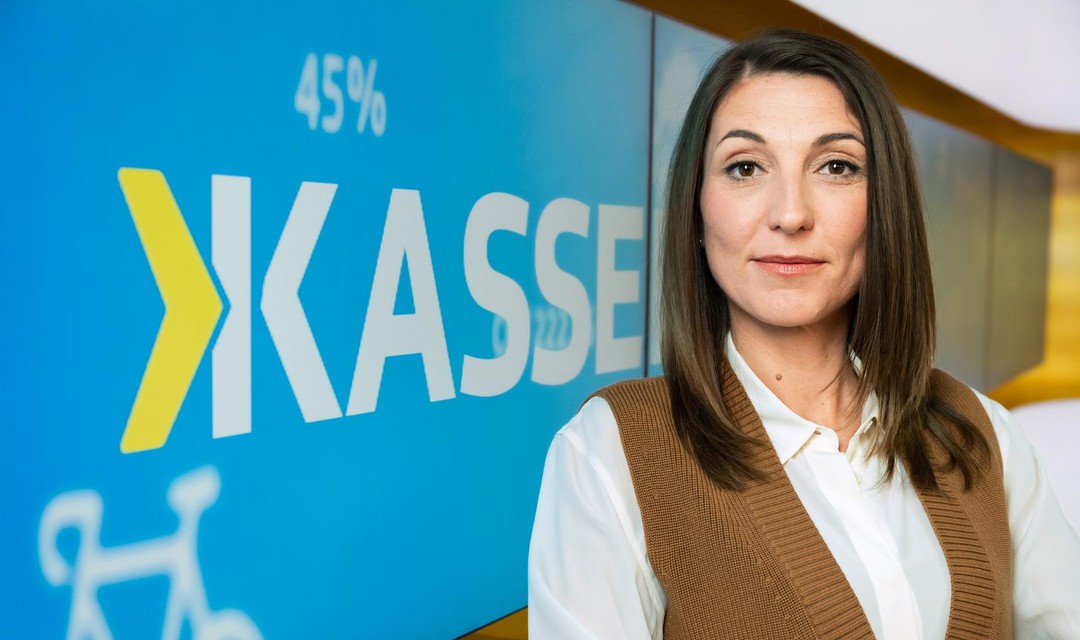 Bettina Ramseier im Kassensturzstudio, vor den Bildschirmen, auf denen Kassensturz steht.