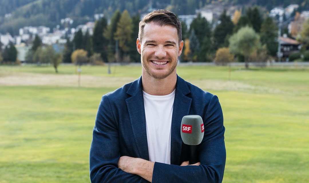 Portrait-Foto von Dario Cologna draussen mit einer Wiese im Hintergrund.