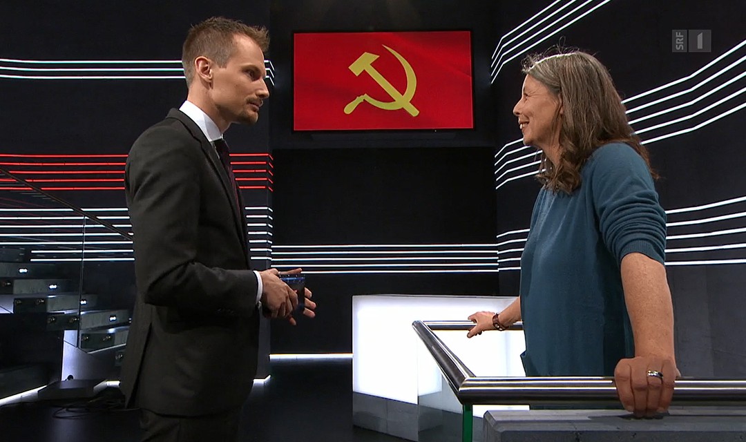 Moderator Jonas Projer befragt Initiantin Ulrike Minkner, im Hintergrund gelber Hammer und gelbe Sichel auf rotem Grund