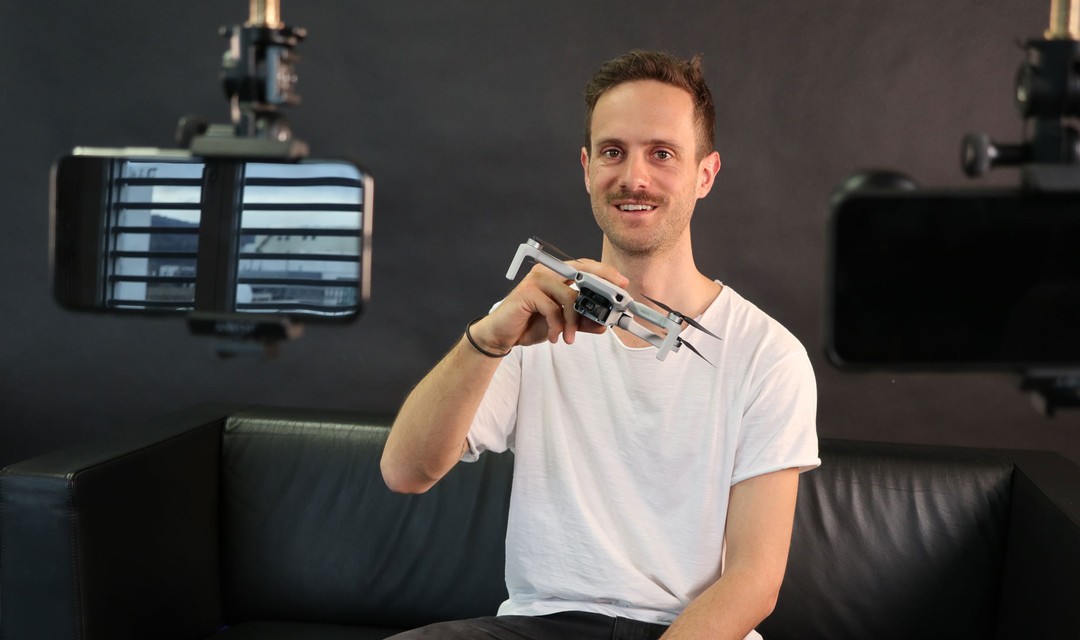 Tinet steht in seinem Studio vor einer LED-Lechte. Im Hintergrund liegen einige Technik-Gadgets.