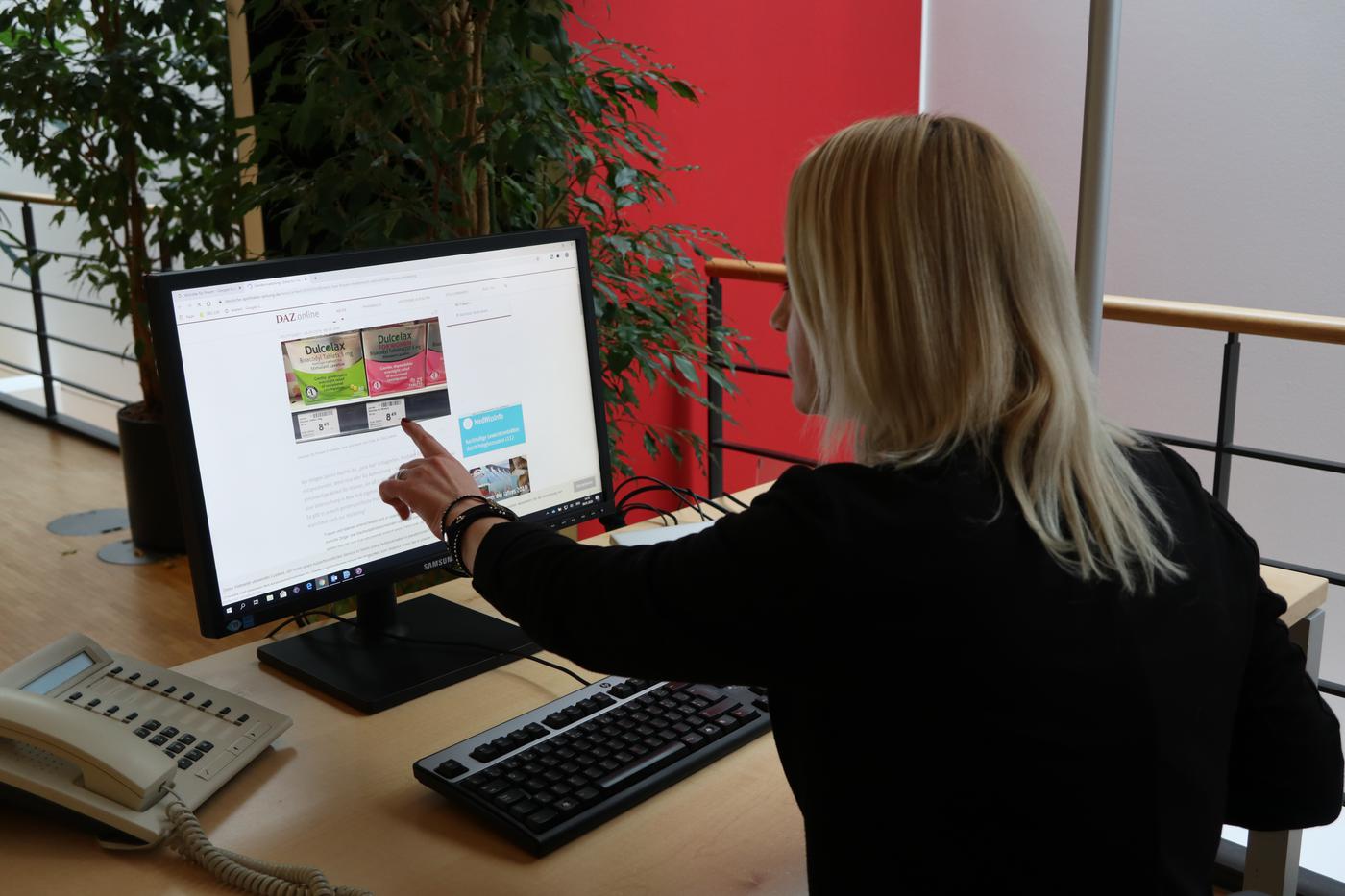 Isabelle hat am PC ein Browserfenster geöffnet, bei welchem Abführmittelverpackungen in grün und pink zu sehen sind