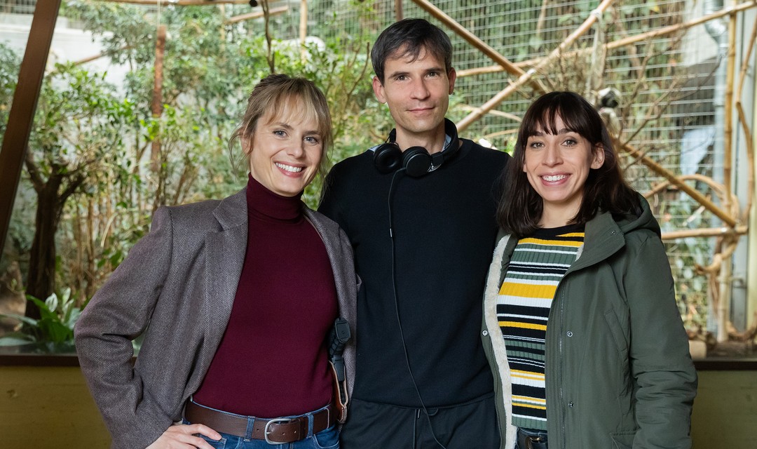 Anna Pieri Zuercher (als Kommissarin Isabelle Grandjean), Regisseur Mike Schärer und Carol Schuler(als Kommissarin Tessa Ott) stehe zusammen vor einem Gehege im Zoo.