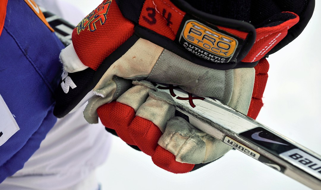 Hand in Hockeyhandschuh hält Eishockey-Stock