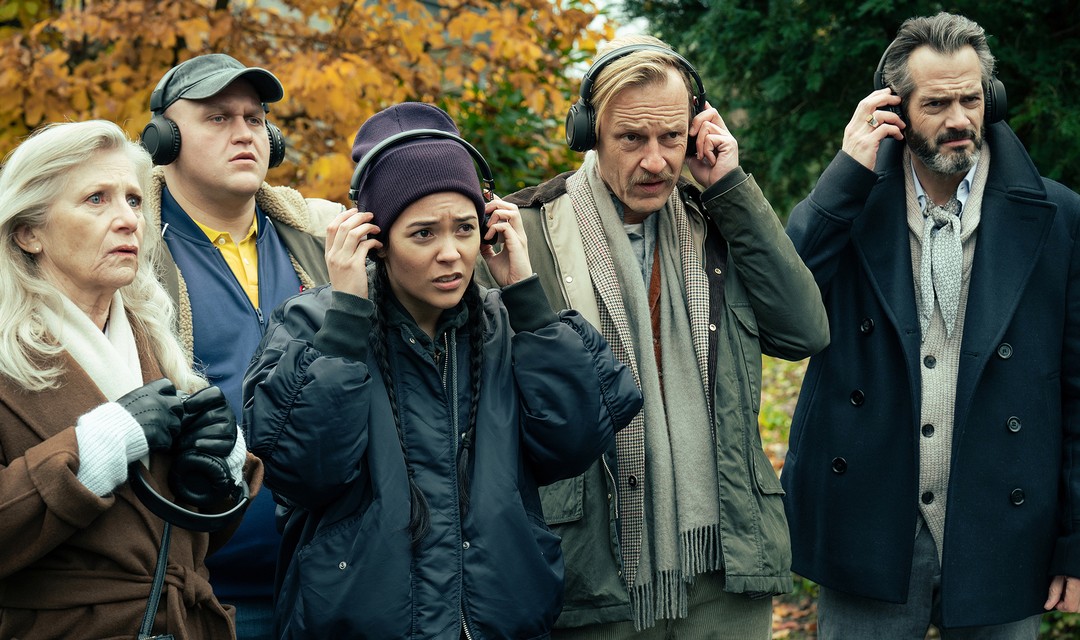 Agotha, Milan, Doro, Hasenfratz und Henning stehen mit Kopfhörern in einem Park