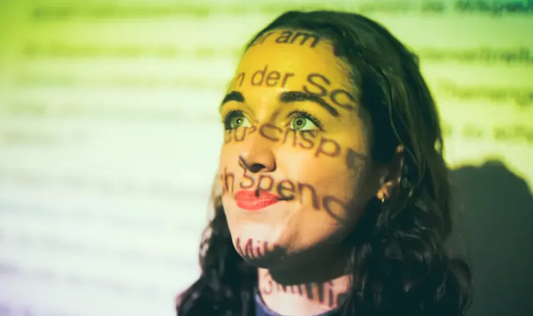 Muriel Straub vor Projektor, der Licht auf ihr Gesicht wirft, projiziert Buchstaben auf Gesicht
