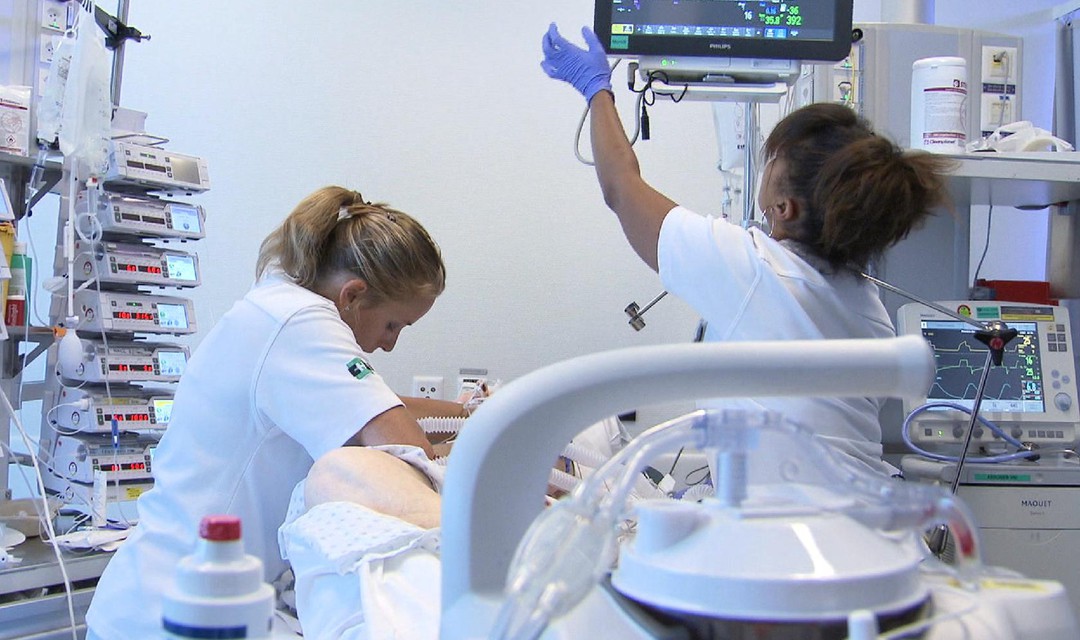 Zwei Pflegerinnen stehen um ein Krankenbett umgeben von diversen Maschinen