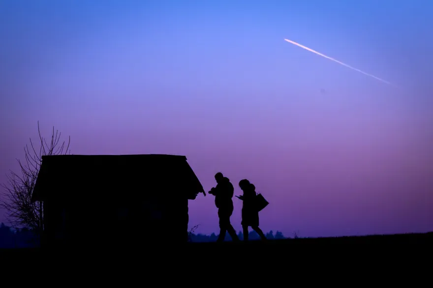 Silhouette einer Hütte in der Dämmerung und zwei Personen davor