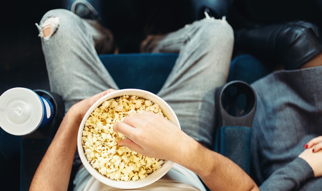 Jemand sitzt im Kino und isst Popcorn