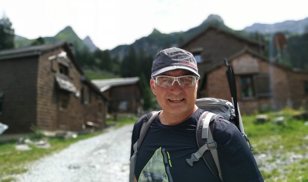 Outdoor-Reporter Marcel Hähni vor Holzhäusern in den Bergen
