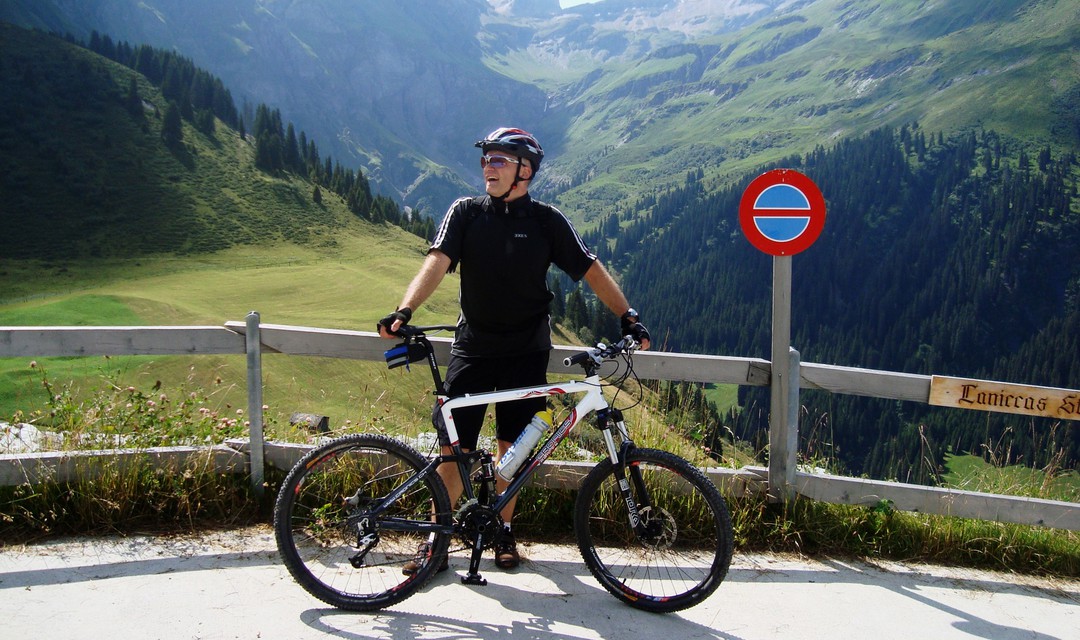 SRF 1 Outdoor-Reporter Marcel Hähni mit dem Velo vor einem Bergpanorama.