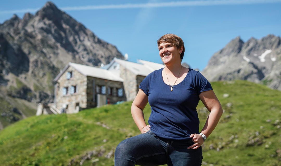 Frau steht auf Wiese vor einem Berg