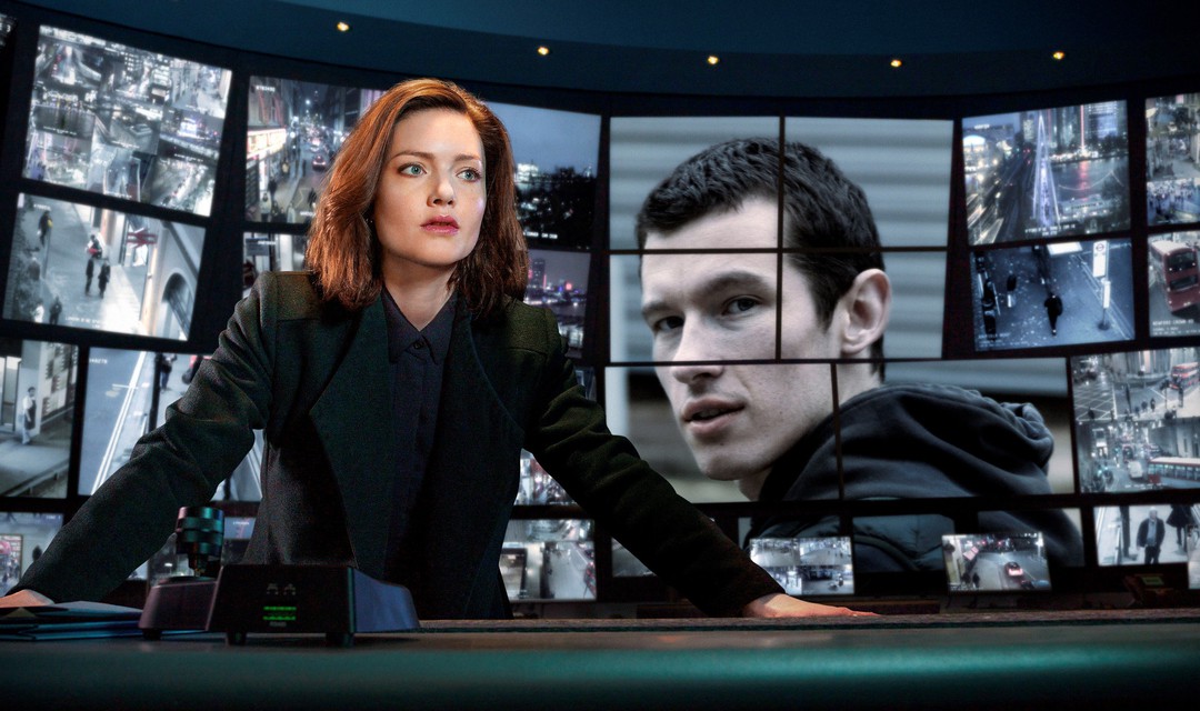 Eine Frau steht in einem Regieraum, hinter ihr sind viele Bildschirme.