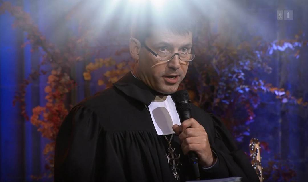 Kirchenbundpräsident Pfarrer Gottfried Locher bei der Predigt in einer Kirche, im Talar mit Lichtstrahlen, die von oben auf ihn herabscheinen