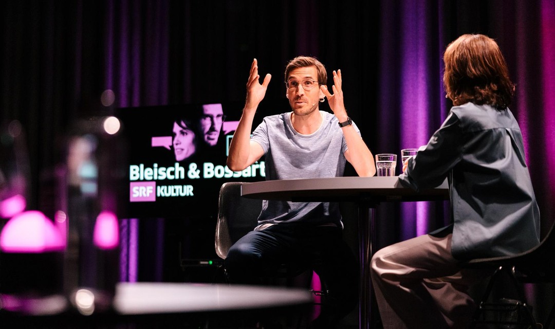 Barbara Bleisch und Yves Bosshardt diskutieren an einem Tisch.