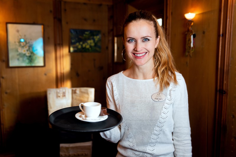 Mirjam Keller steht im Hotel und hält ein Serviertablett mit einem frischen Kaffee in den Händen.