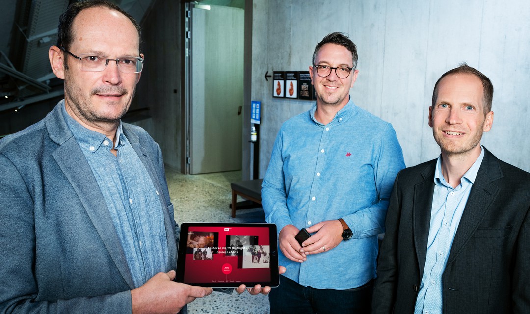 Christian Vogg, Stefan Weber und Kai Jauslin stehen zusammen und halten ein Tablet in der Hand