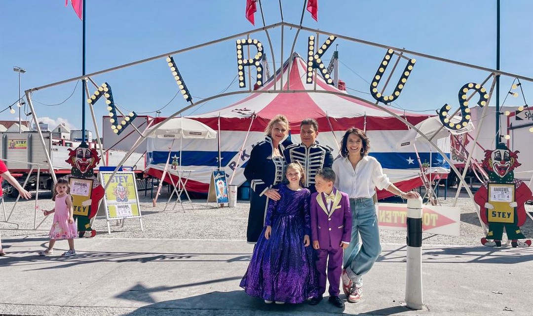 Das Foto zeigt die Zirkusfamilie Stey mit Mutter, Vater sowie Söhnchen und Töchterchen. Daneben steht Mona Vetsch. Im Hintergrund steht das Zirkuszelt. Davor ist ein Torbogengerüst aufgebaut. Darauf prangen die mit Lämpchen versehenen Lettern "Zirkus".