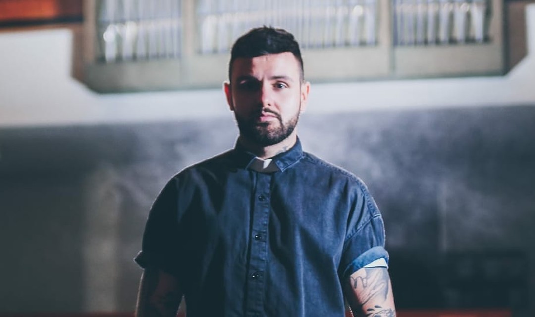 Host Livio Carlin steht in einer Kirche, im Hintergrund ist die Kirchenorgel zu sehen