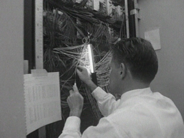 Ein Mann sortiert Kabel bei einem Computer.