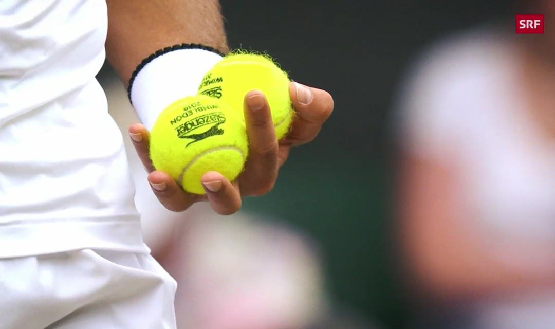 Hand hält zwei Tennisbälle die mit Wimbledon 2019 beschriftet sind 