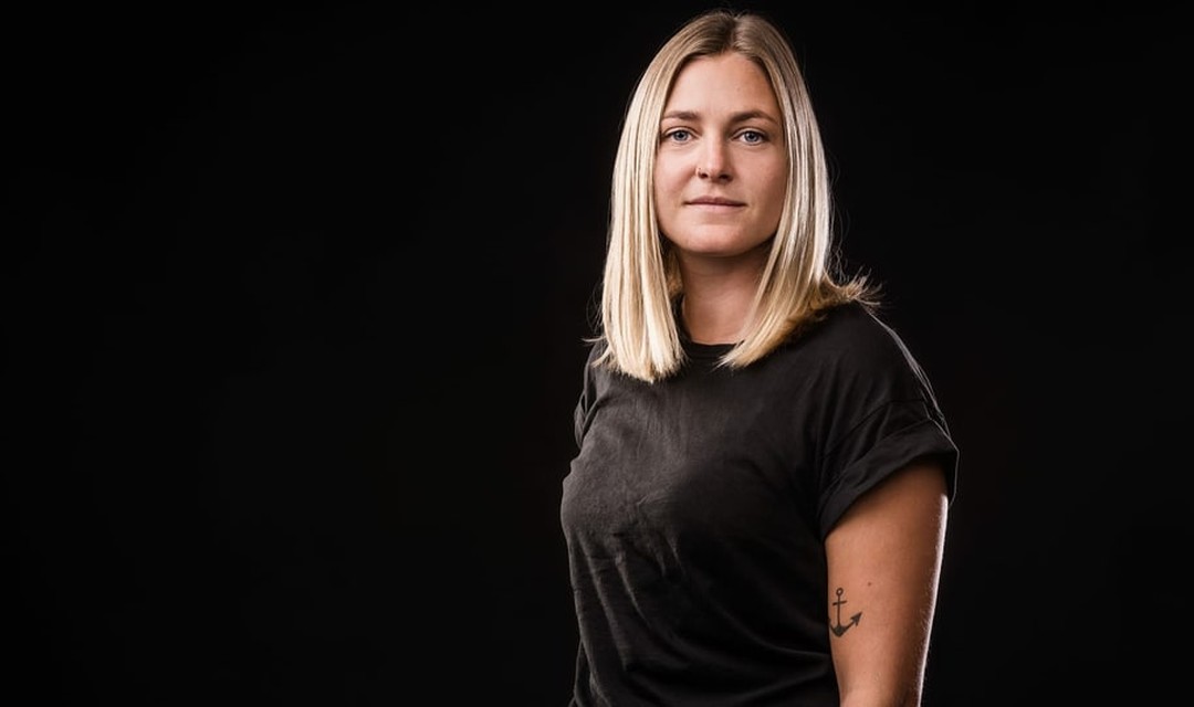 Porträt von Host Gina Schuler vor einem schwarzen Hintergrund