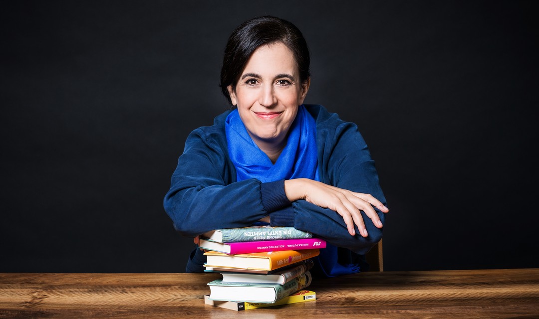 "Literaturclub"-Moderatorin Jennifer Khakshouri an einem Tisch mit einem Stapel Bücher