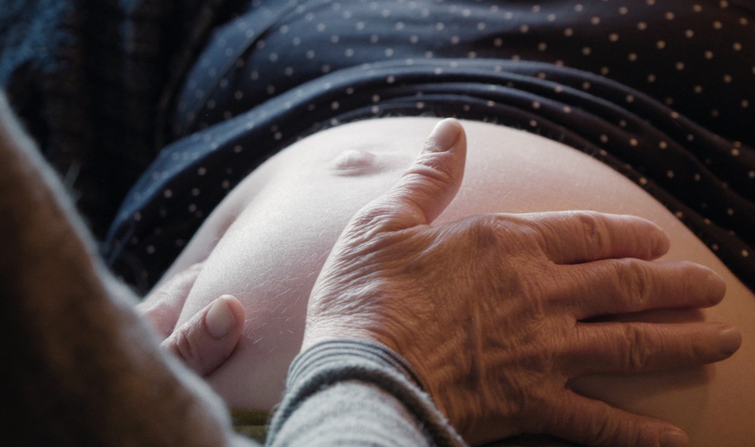 Foto: Hände die auf den Bauch einer Schwangeren gelegt sind