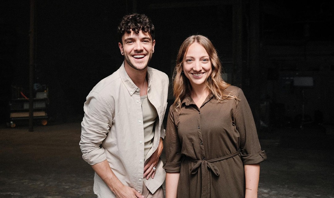 Foto von Luca Hänni und Anna Zöllig, welche nebeneinander stehen, vor dunklem Hintergrund..