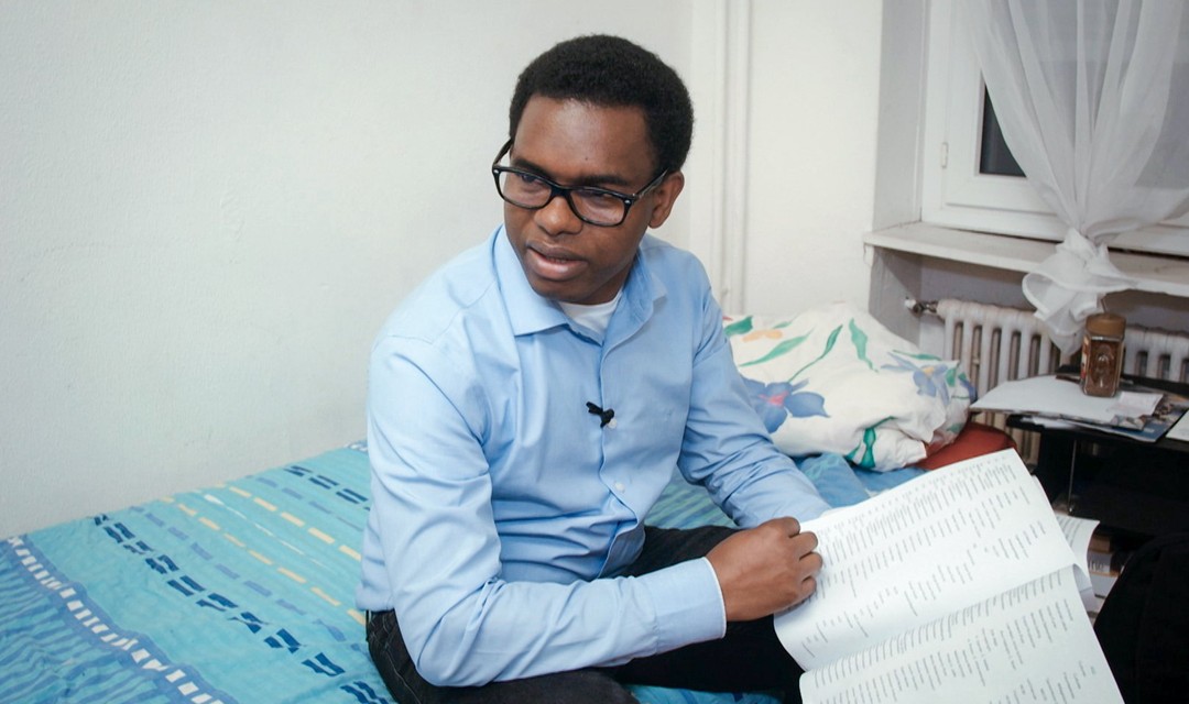 Amine sitzt auf seinem Bett in der Asylunterkunft